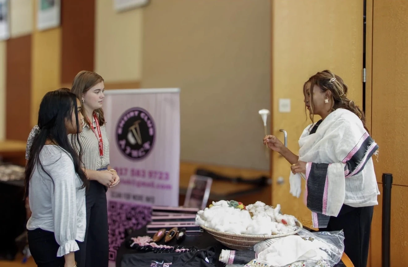 Woman demonstrating traditional cotton spinning to visitors at a cultural event